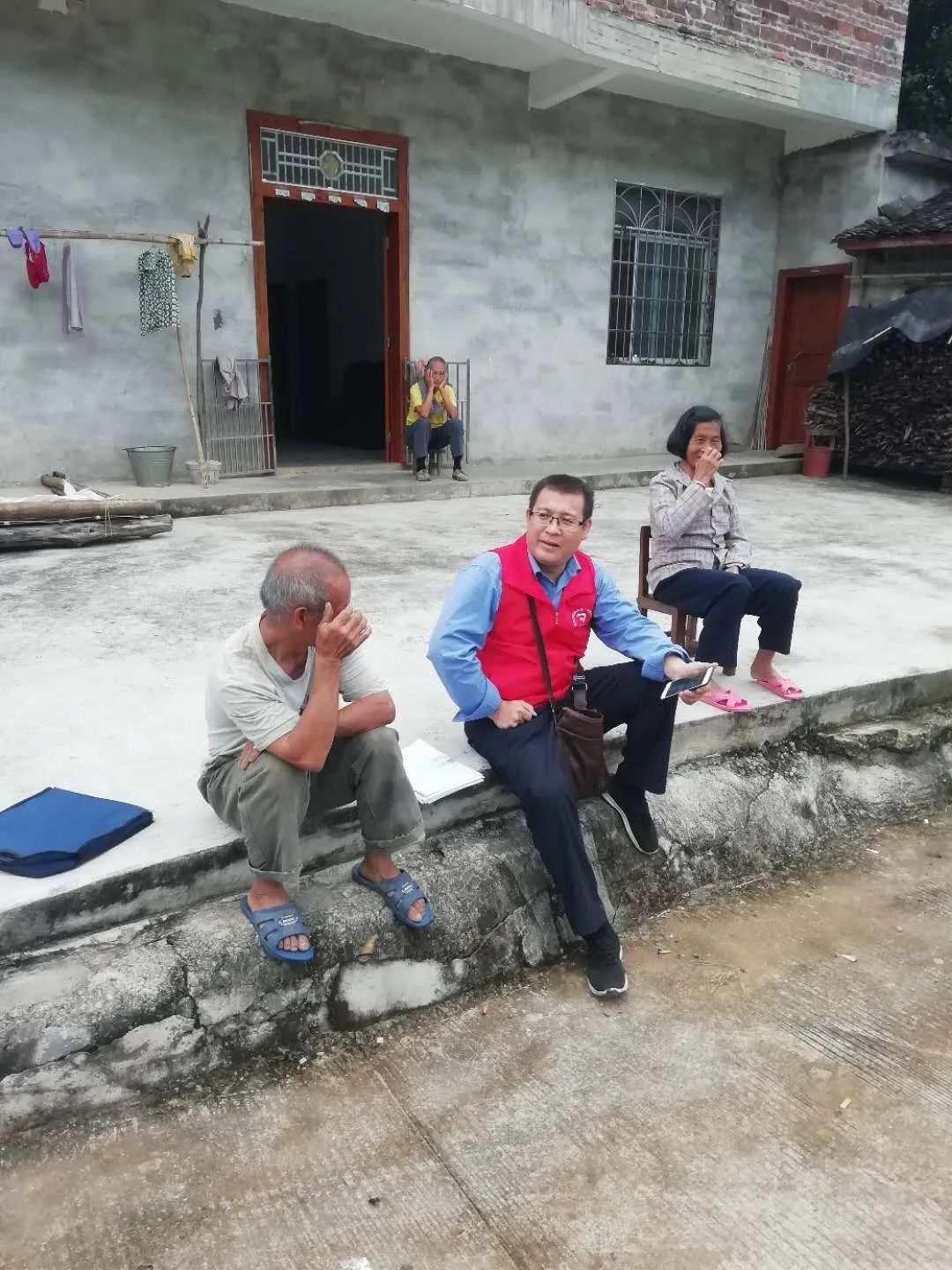 图为许杰华（前排居中）到农户家中了解村情，商讨产业发展思路